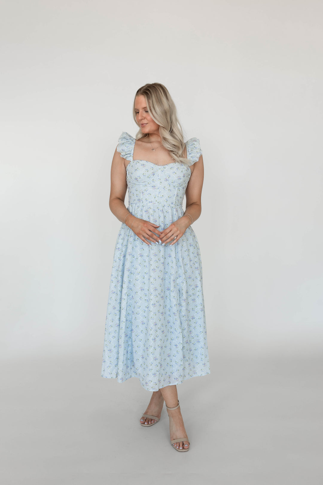 Woman wearing blue eyelet floral midi dress with corset back and side slit. 
