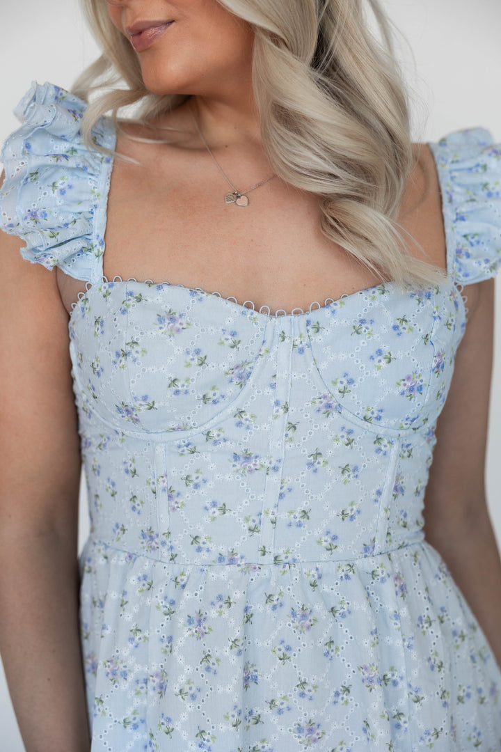 Woman wearing blue eyelet floral midi dress with corset back and side slit. 