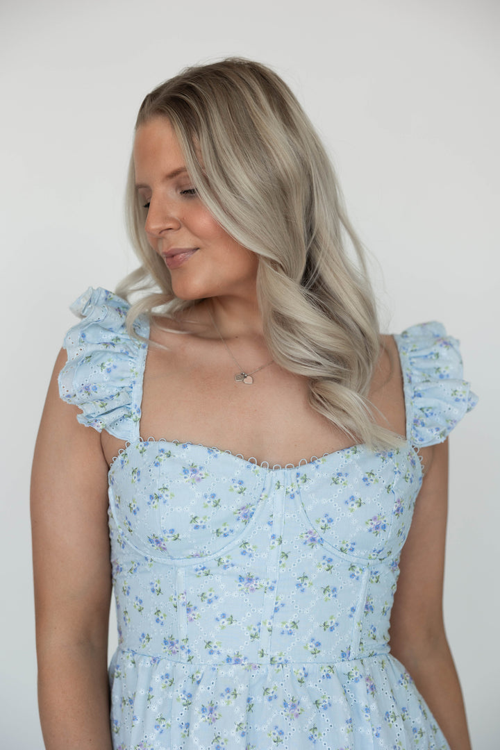 Woman wearing blue eyelet floral midi dress with corset back and side slit. 