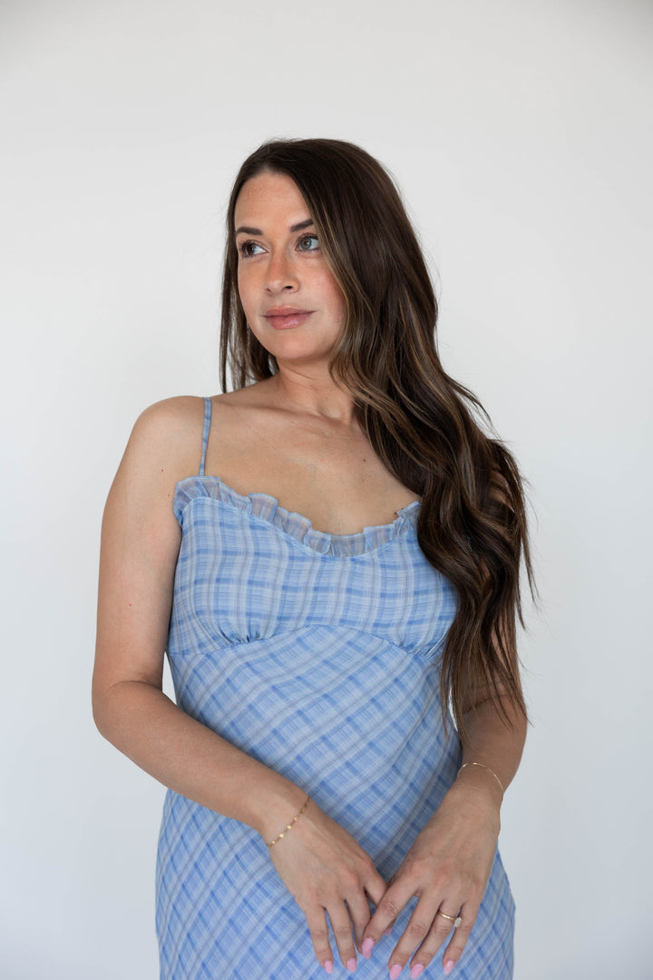 Woman wearing a blue plaid maxi dress with adjustable spaghetti straps. 