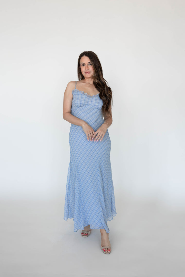 Woman wearing a blue plaid maxi dress with adjustable spaghetti straps. 