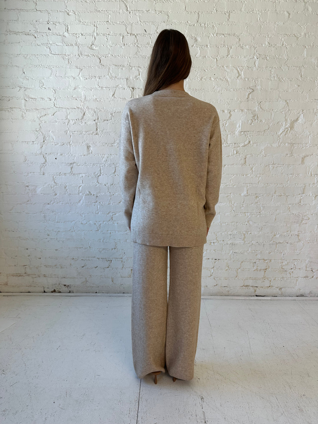 Woman wearing oatmeal colored two piece sweater set with kitten heel.