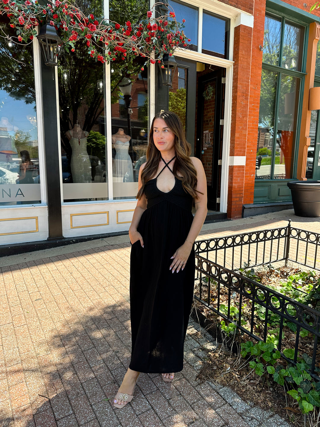 Woman wearing black contrast midi dress with a crochet criss cross halter top, and gauze bottom.