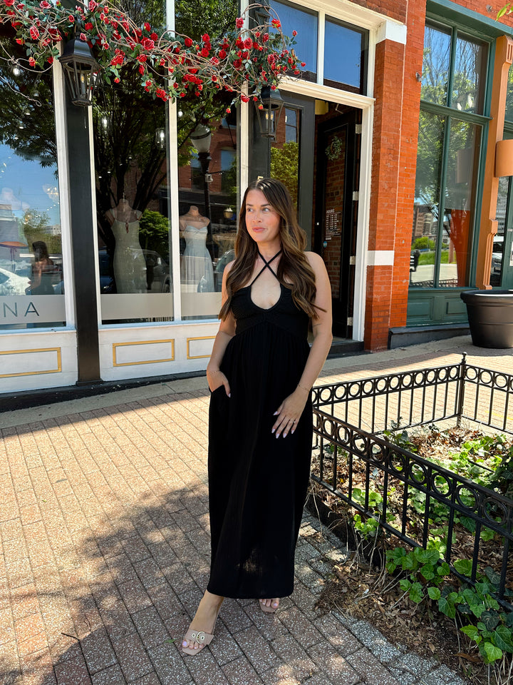 Woman wearing black contrast midi dress with a crochet criss cross halter top, and gauze bottom.