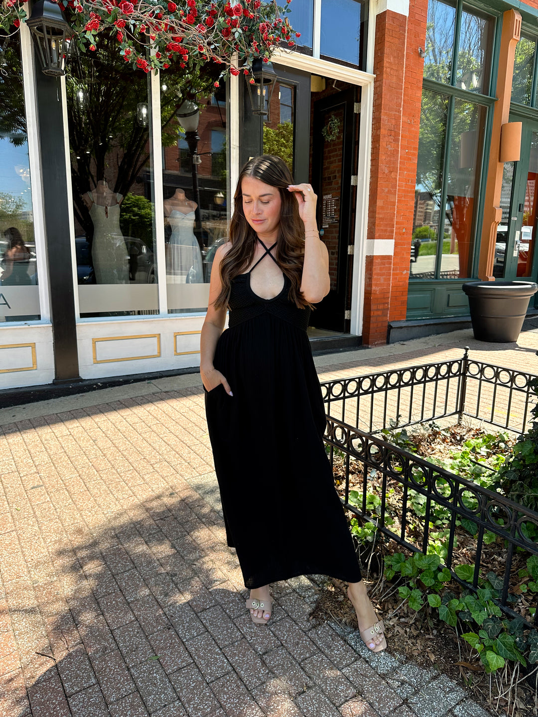 Woman wearing black contrast midi dress with a crochet criss cross halter top, and gauze bottom.