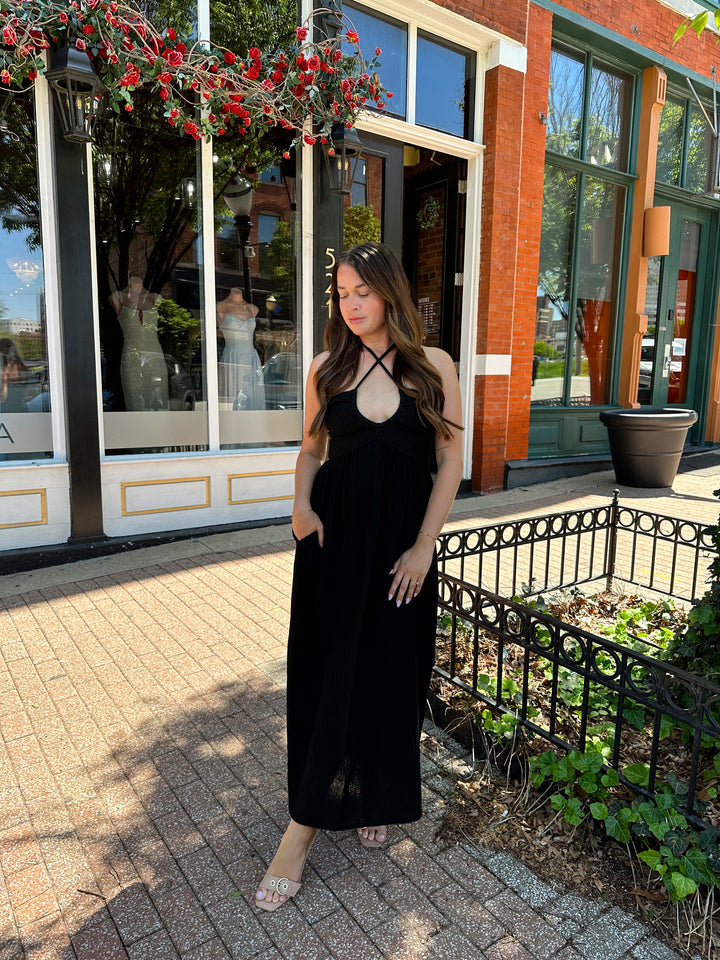 Woman wearing black contrast midi dress with a crochet criss cross halter top, and gauze bottom.