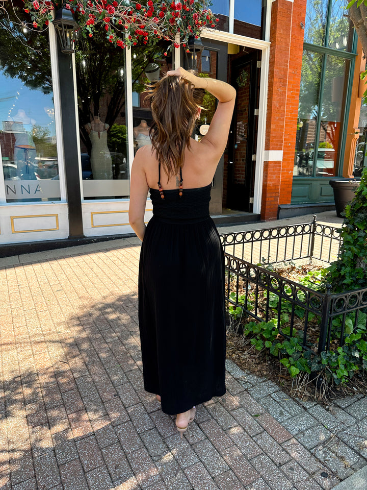Woman wearing black contrast midi dress with a crochet criss cross halter top, and gauze bottom.
