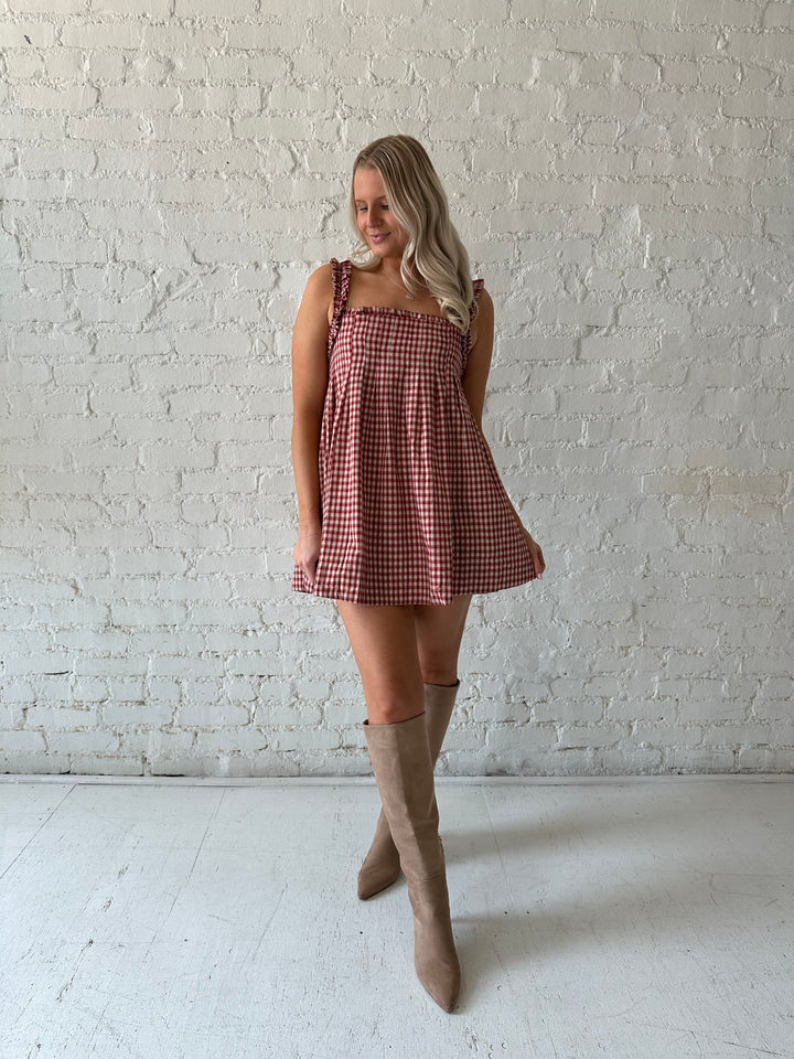 Woman wearing red and beige plaid babydoll mini dress with suede beige boots.