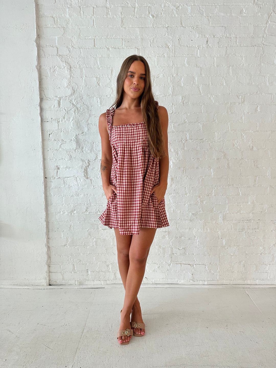 Woman wearing red and beige plaid babydoll style mini dress with gathered neckline, and gathered straps.