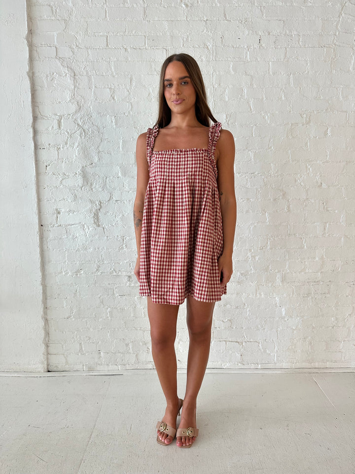 Woman wearing red and beige plaid babydoll style mini dress with gathered neckline, and gathered straps.