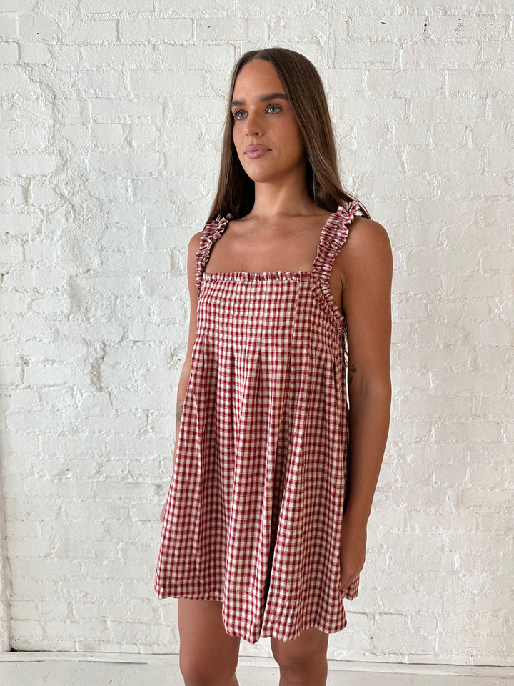 Woman wearing red and beige plaid babydoll style mini dress with gathered neckline, and gathered straps.