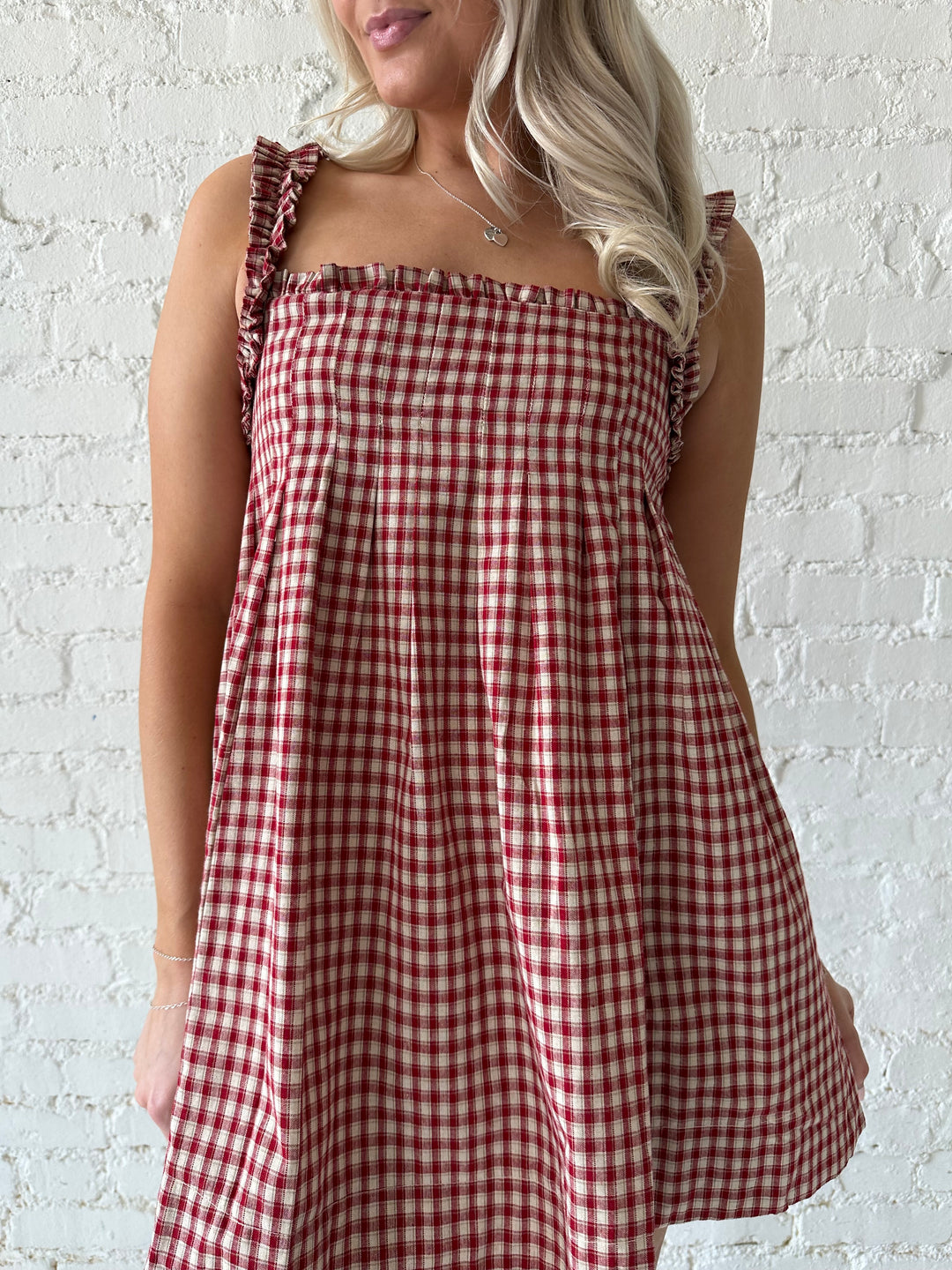 Woman wearing red and beige plaid babydoll mini dress with suede beige boots.