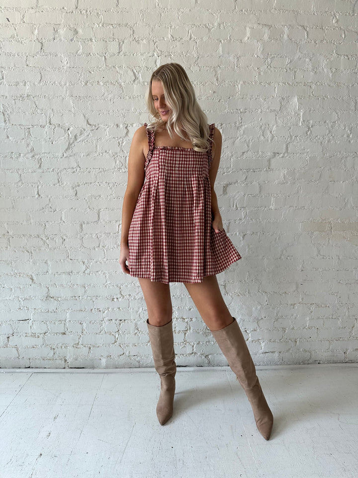 Woman wearing red and beige plaid babydoll mini dress with suede beige boots.