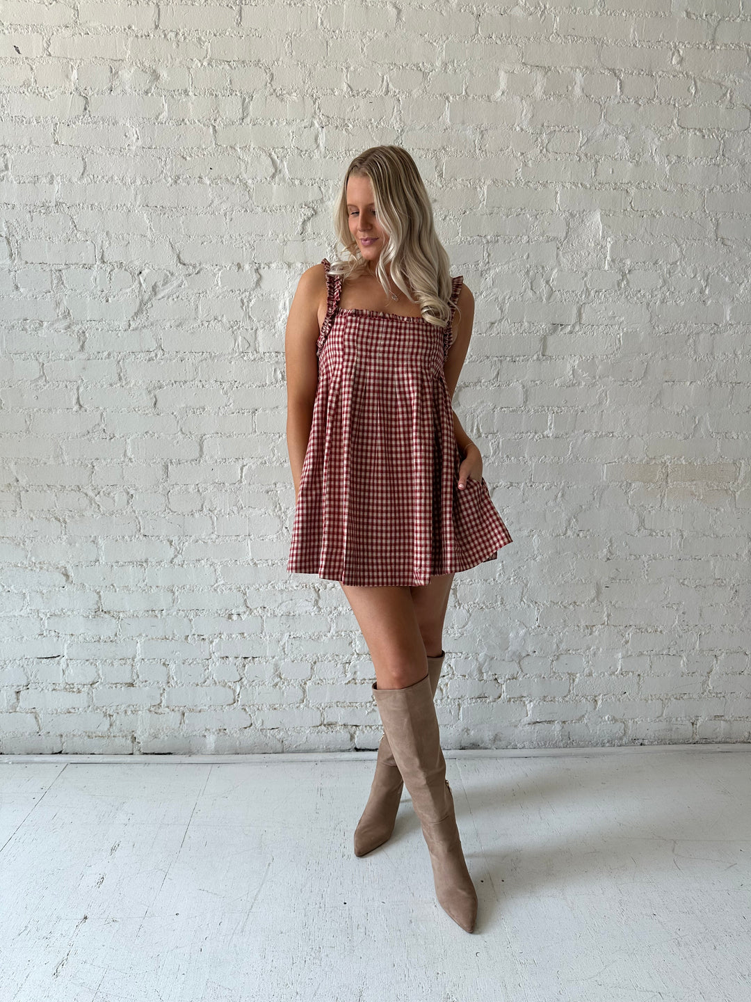 Woman wearing red and beige plaid babydoll mini dress with suede beige boots.