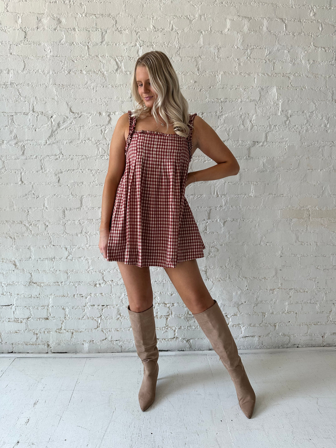 Woman wearing red and beige plaid babydoll mini dress with suede beige boots.