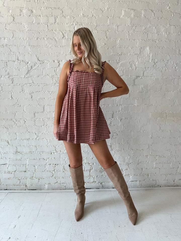 Woman wearing red and beige plaid babydoll mini dress with suede beige boots.