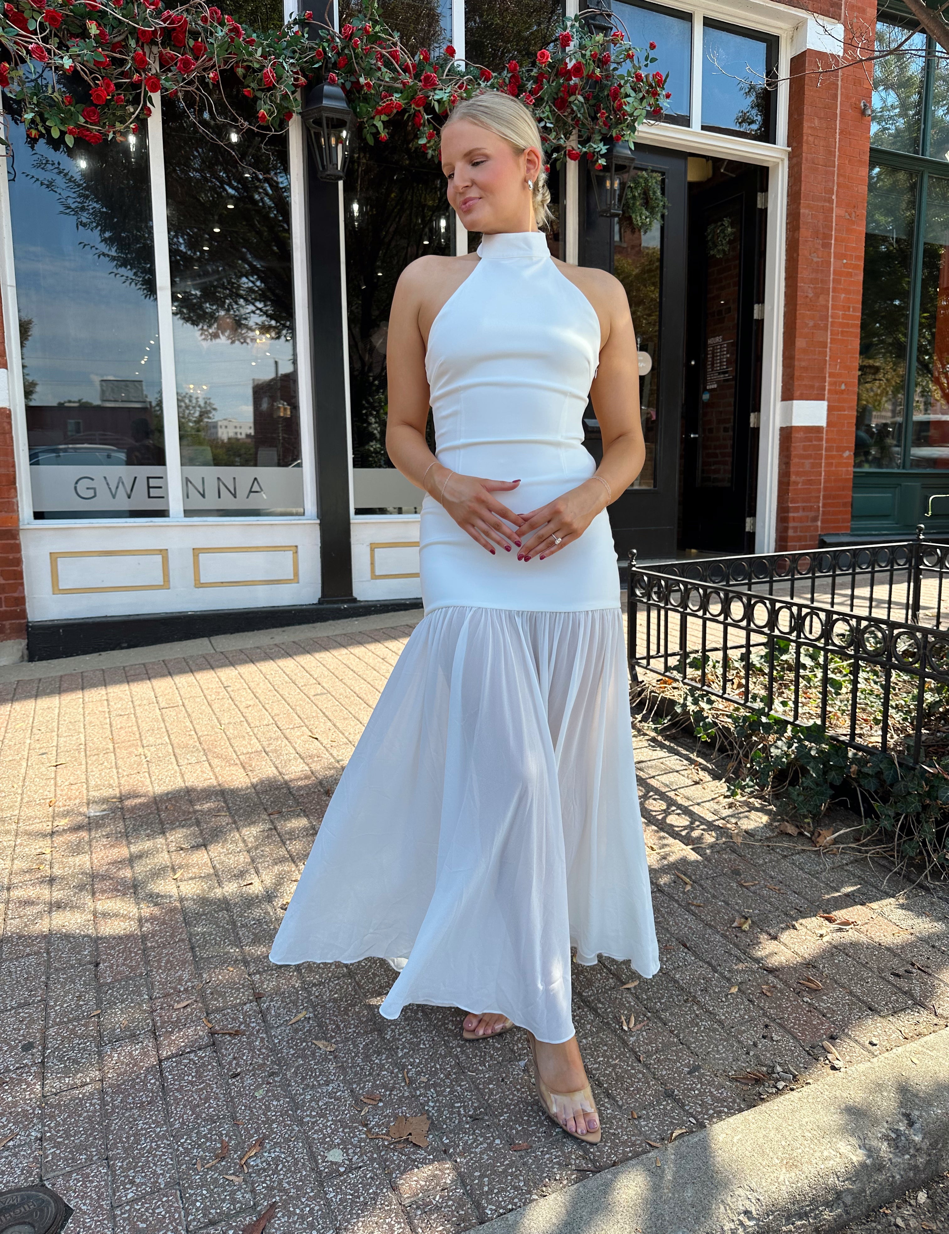 Woman wearing white halter neckline and sheer skirt overlay and open back. 