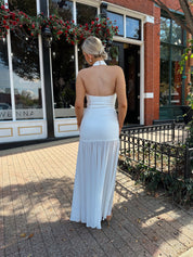 Woman wearing white halter neckline and sheer skirt overlay and open back. 