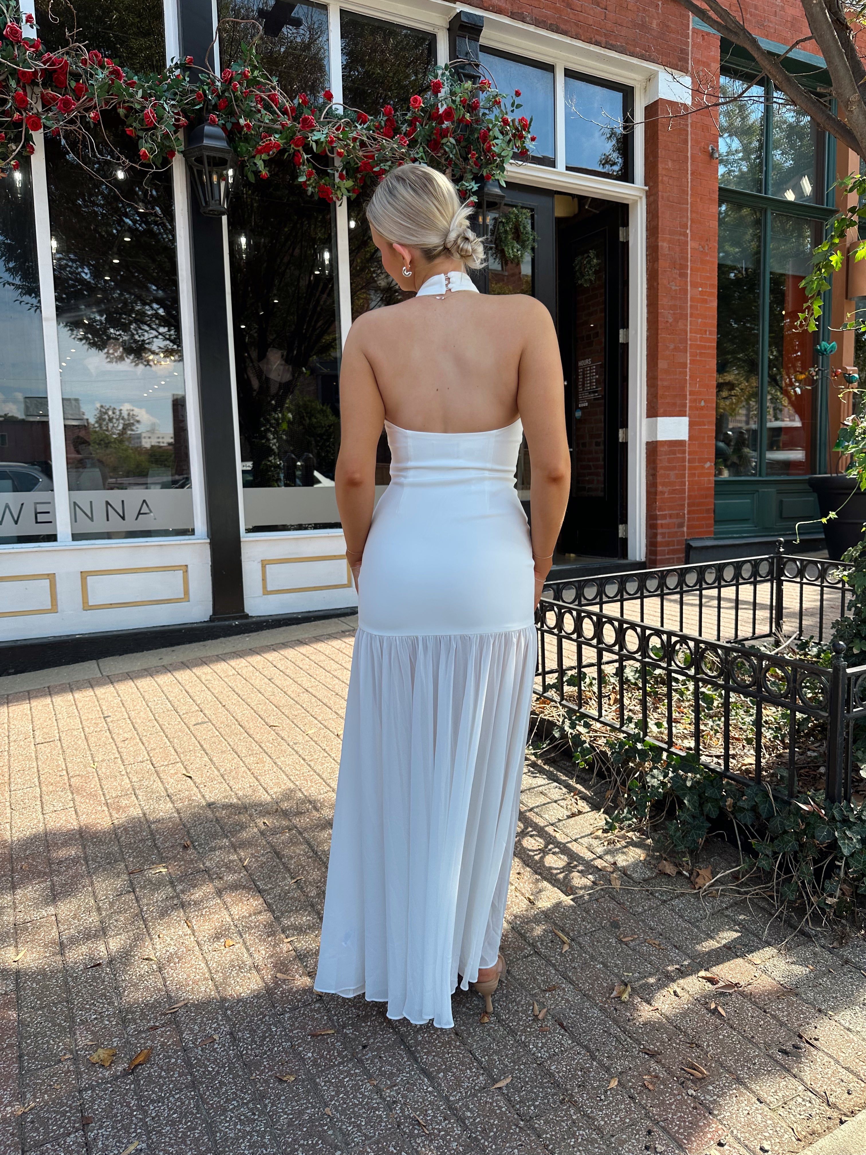 Woman wearing white halter neckline and sheer skirt overlay and open back. 