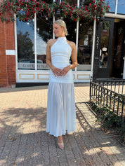 Woman wearing white halter neckline and sheer skirt overlay and open back. 
