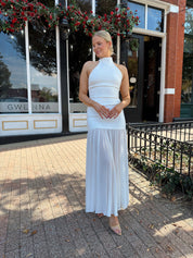 Woman wearing white halter neckline and sheer skirt overlay and open back. 