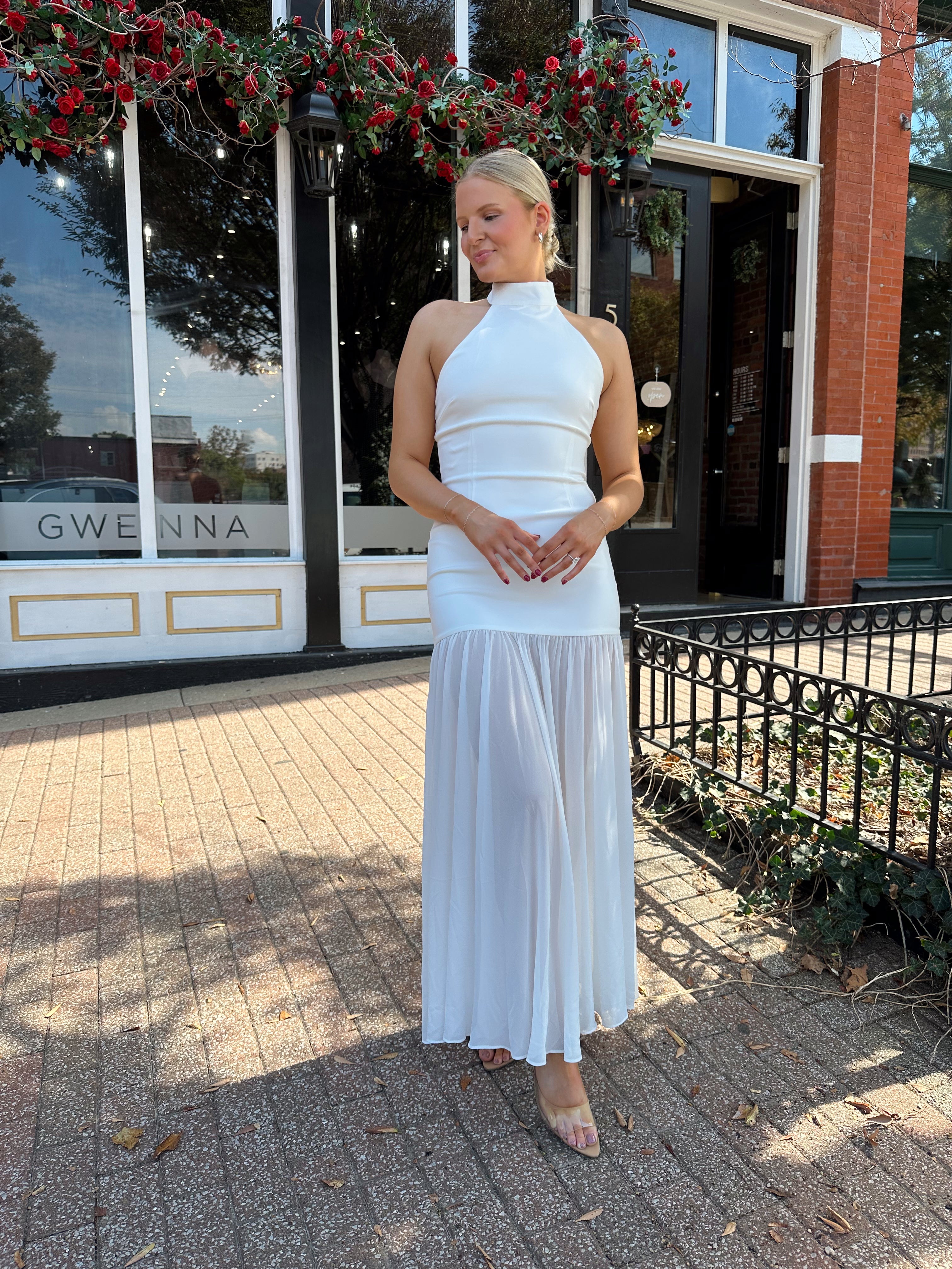 Woman wearing white halter neckline and sheer skirt overlay and open back. 
