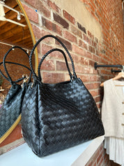 Black woven shoulder bag with braided handles and gold hardware detail