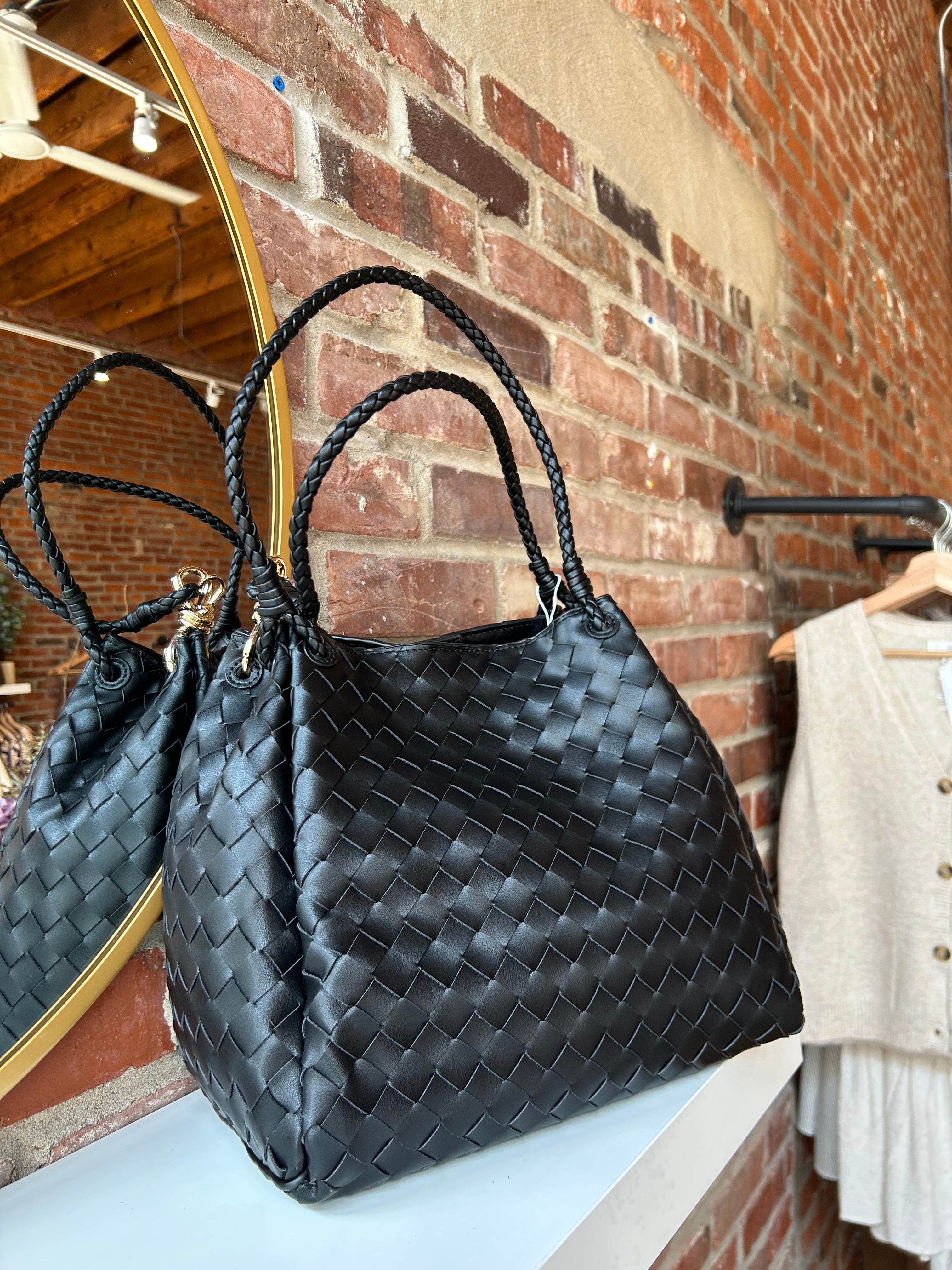 Black woven shoulder bag with braided handles and gold hardware detail