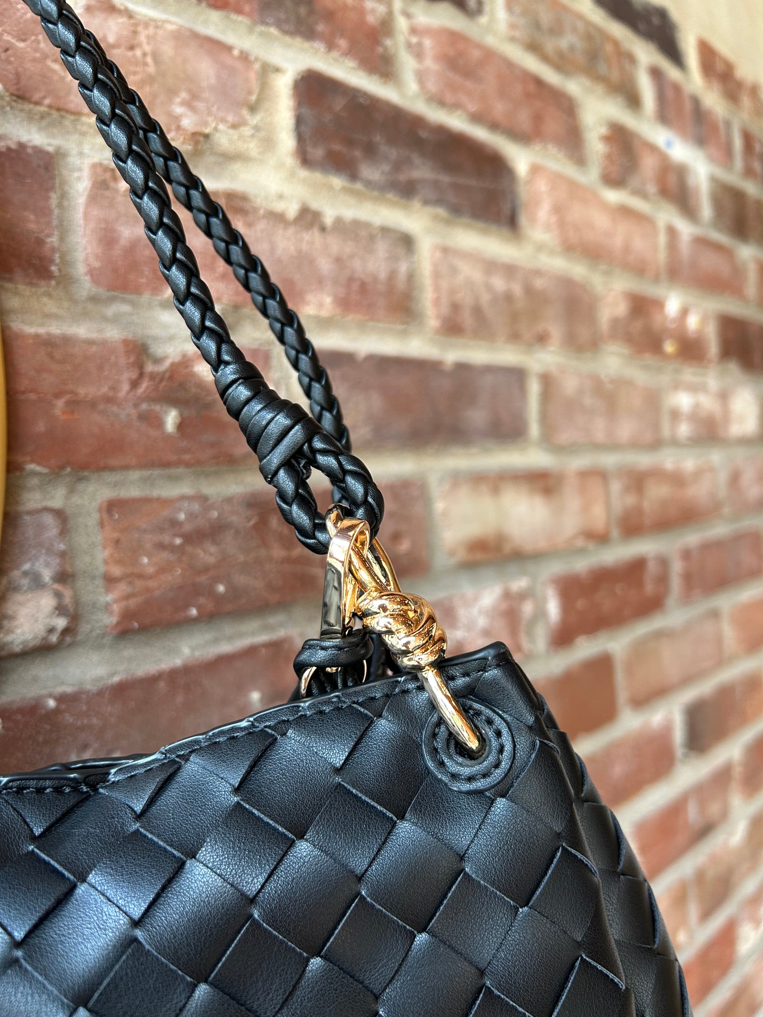 Black woven shoulder bag with braided handles and gold hardware detail
