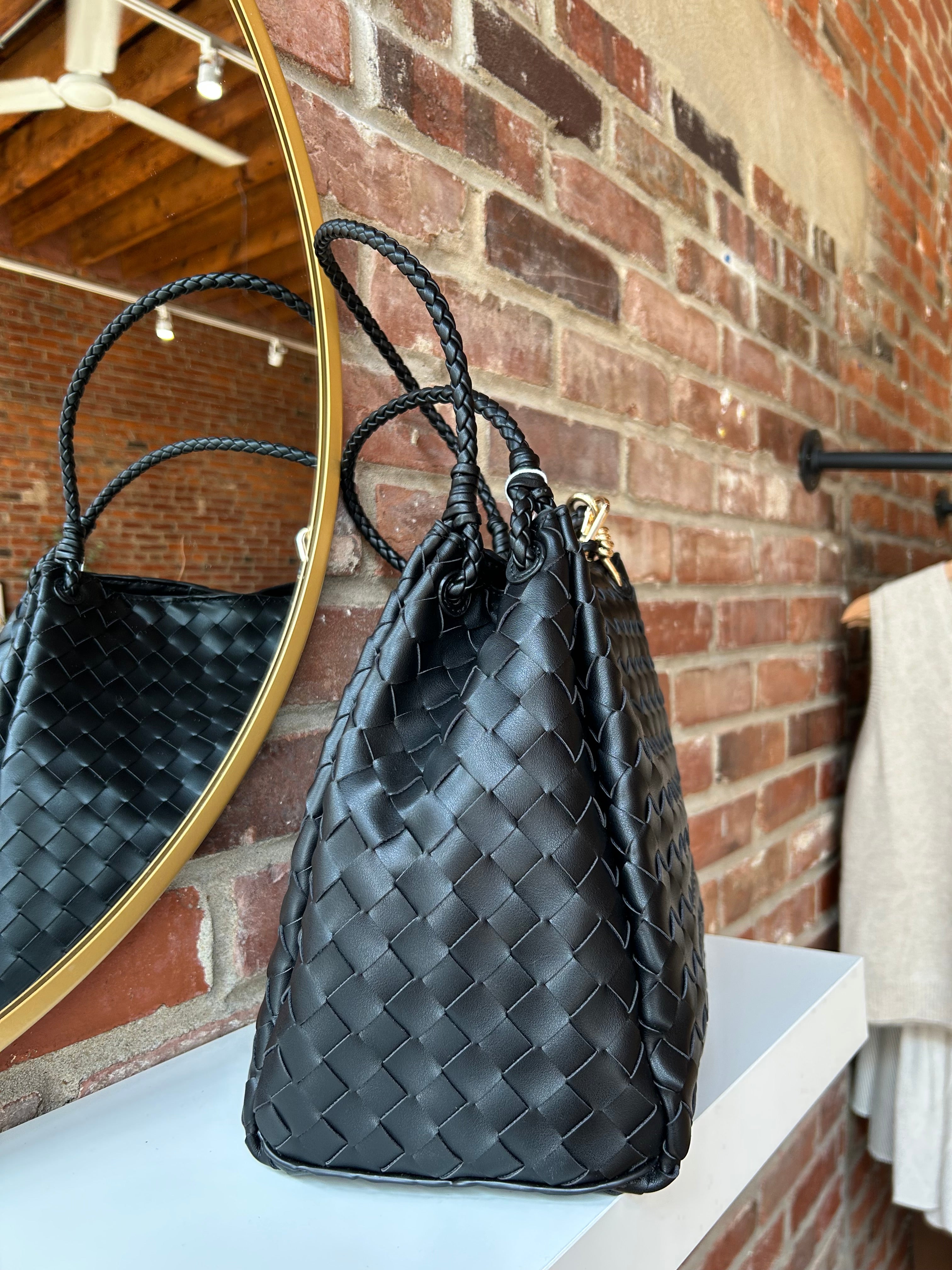 Black woven shoulder bag with braided handles and gold hardware detail