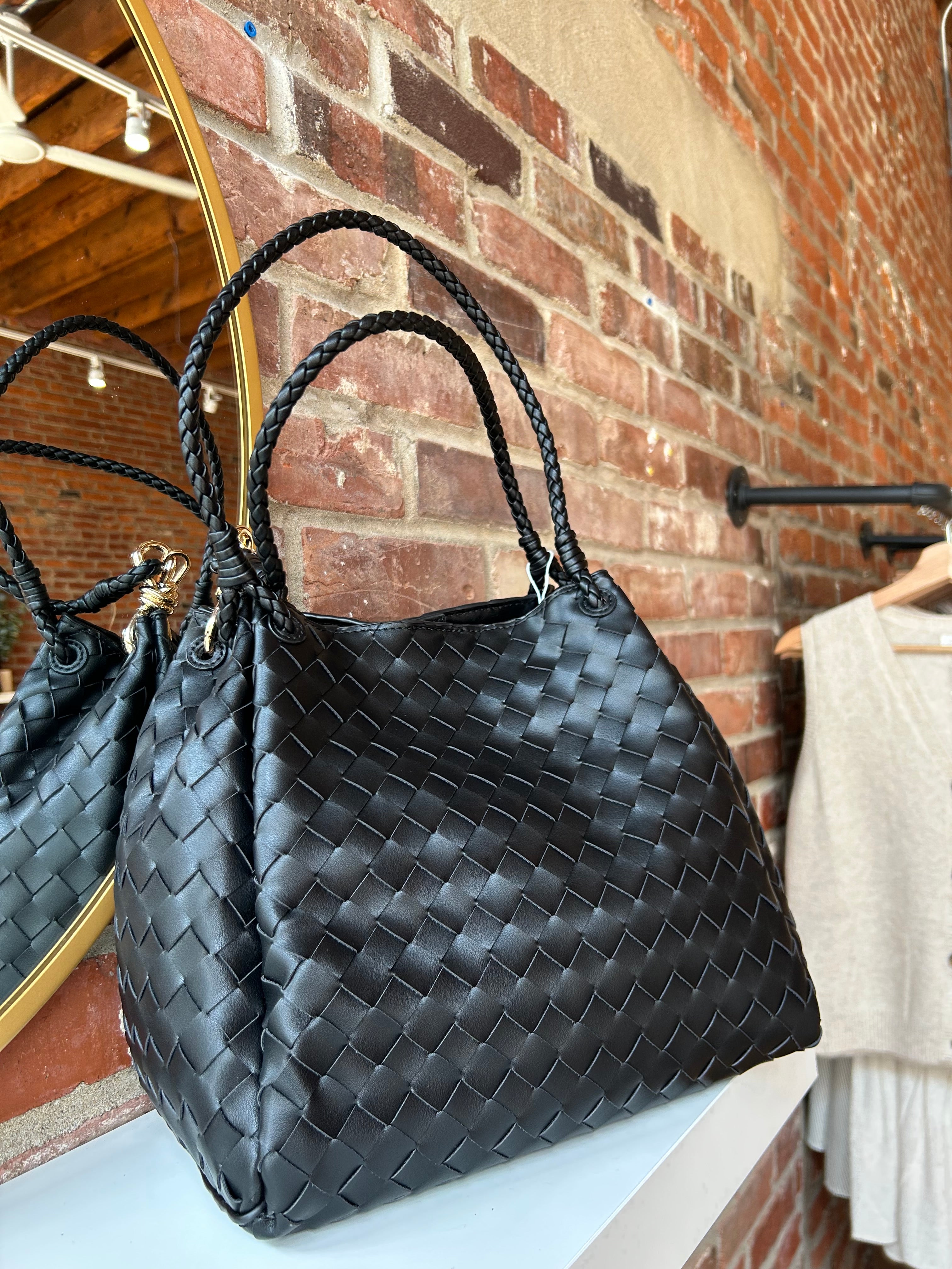 Black woven shoulder bag with braided handles and gold hardware detail