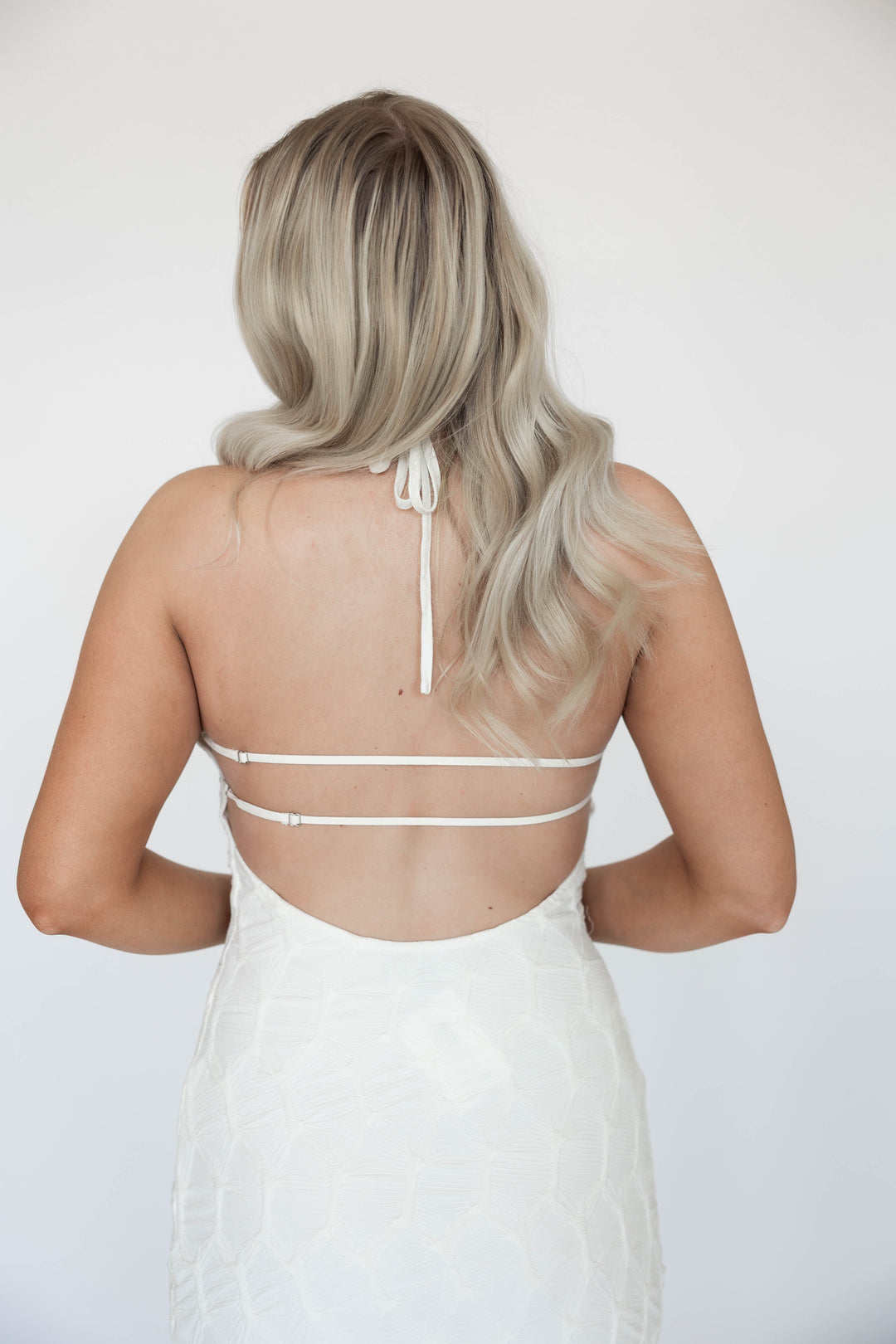 Woman wearing textured ivory knit maxi dress with open back. 
