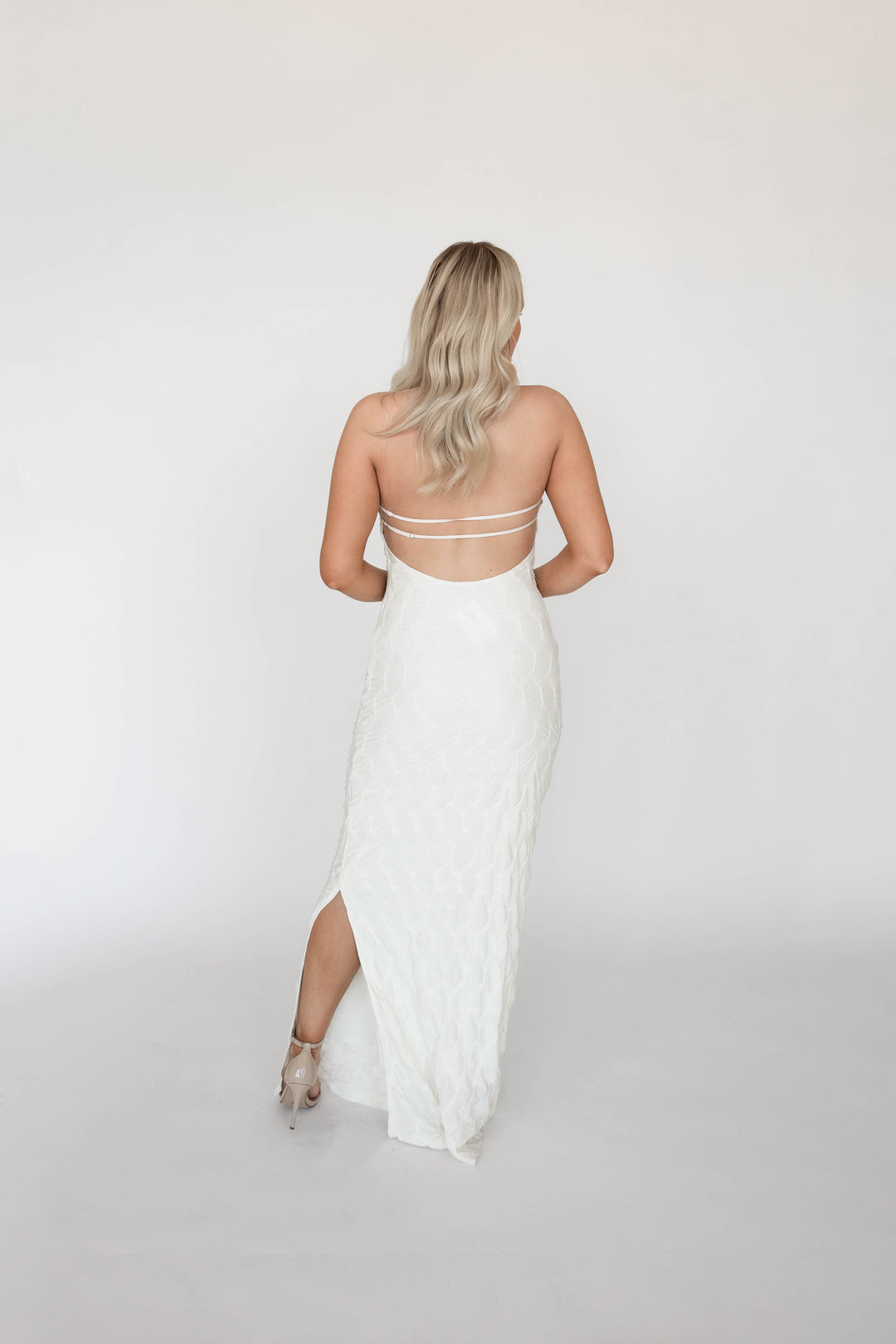 Woman wearing textured ivory knit maxi dress with open back. 