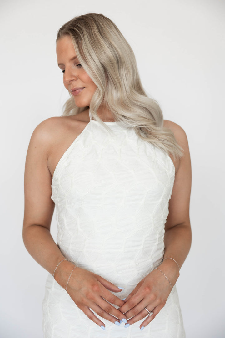 Woman wearing textured ivory knit maxi dress with open back. 