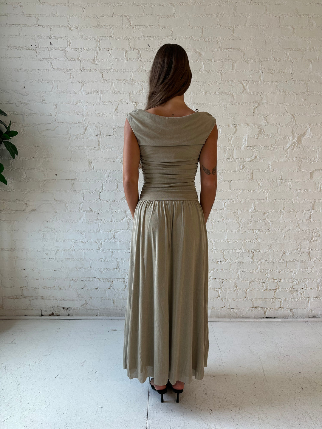 Woman wearing taupe midi dress with ruched sides and cowl neckline. 