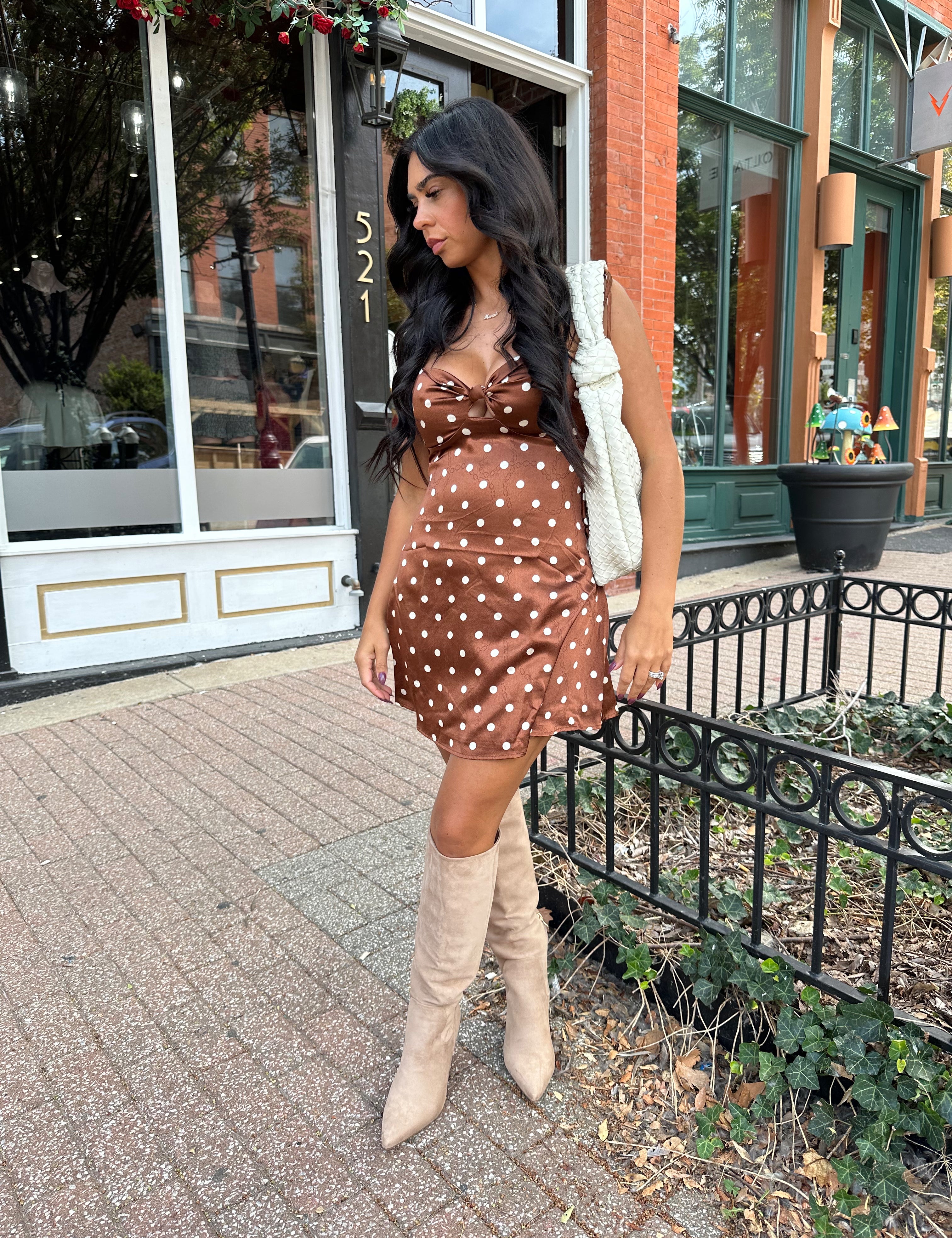 Woman wearing copper brown satin mini dress with white polka dots and self tie straps.