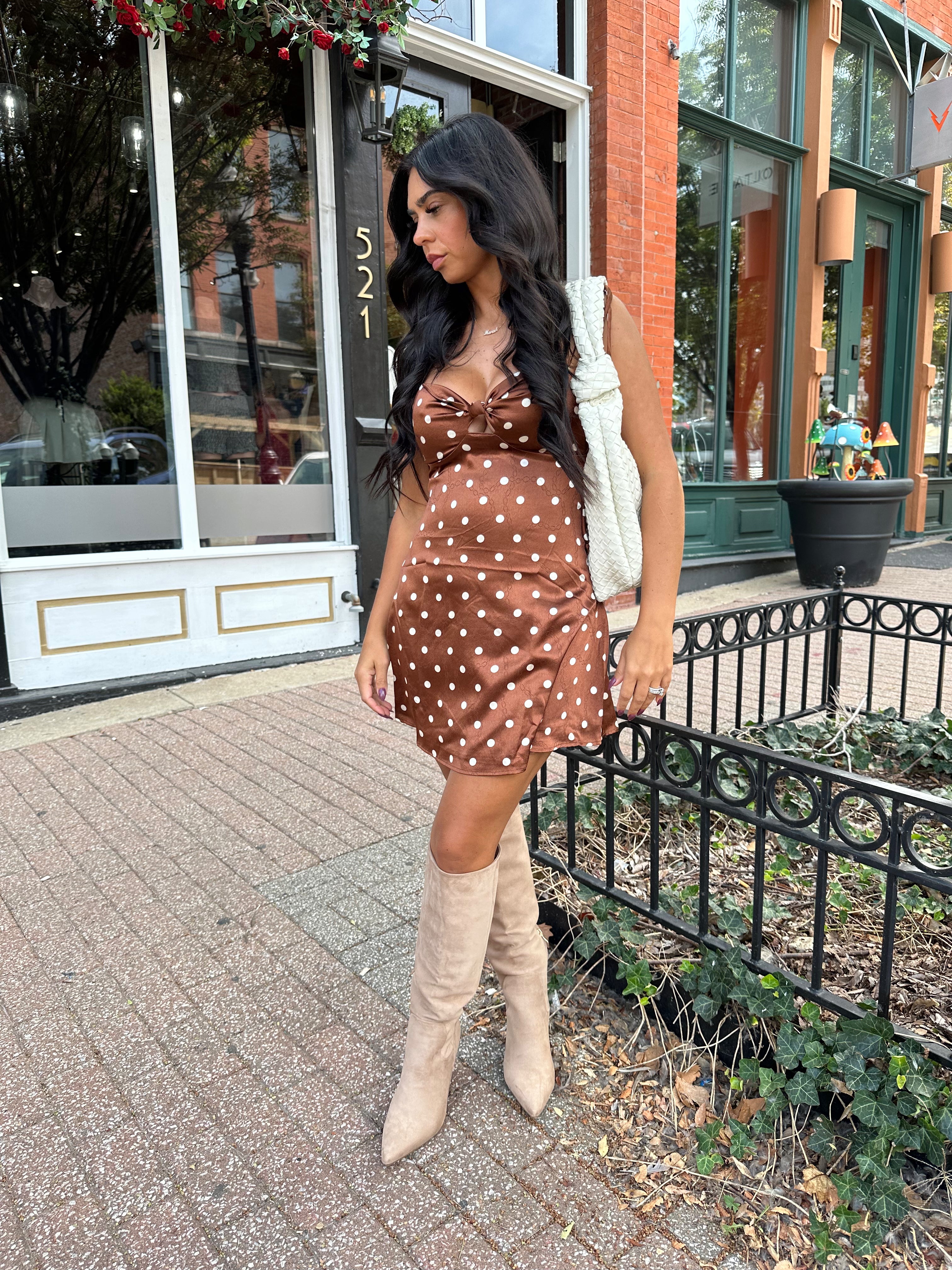 Woman wearing copper brown satin mini dress with white polka dots and self tie straps.