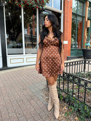 Woman wearing copper brown satin mini dress with white polka dots and self tie straps.