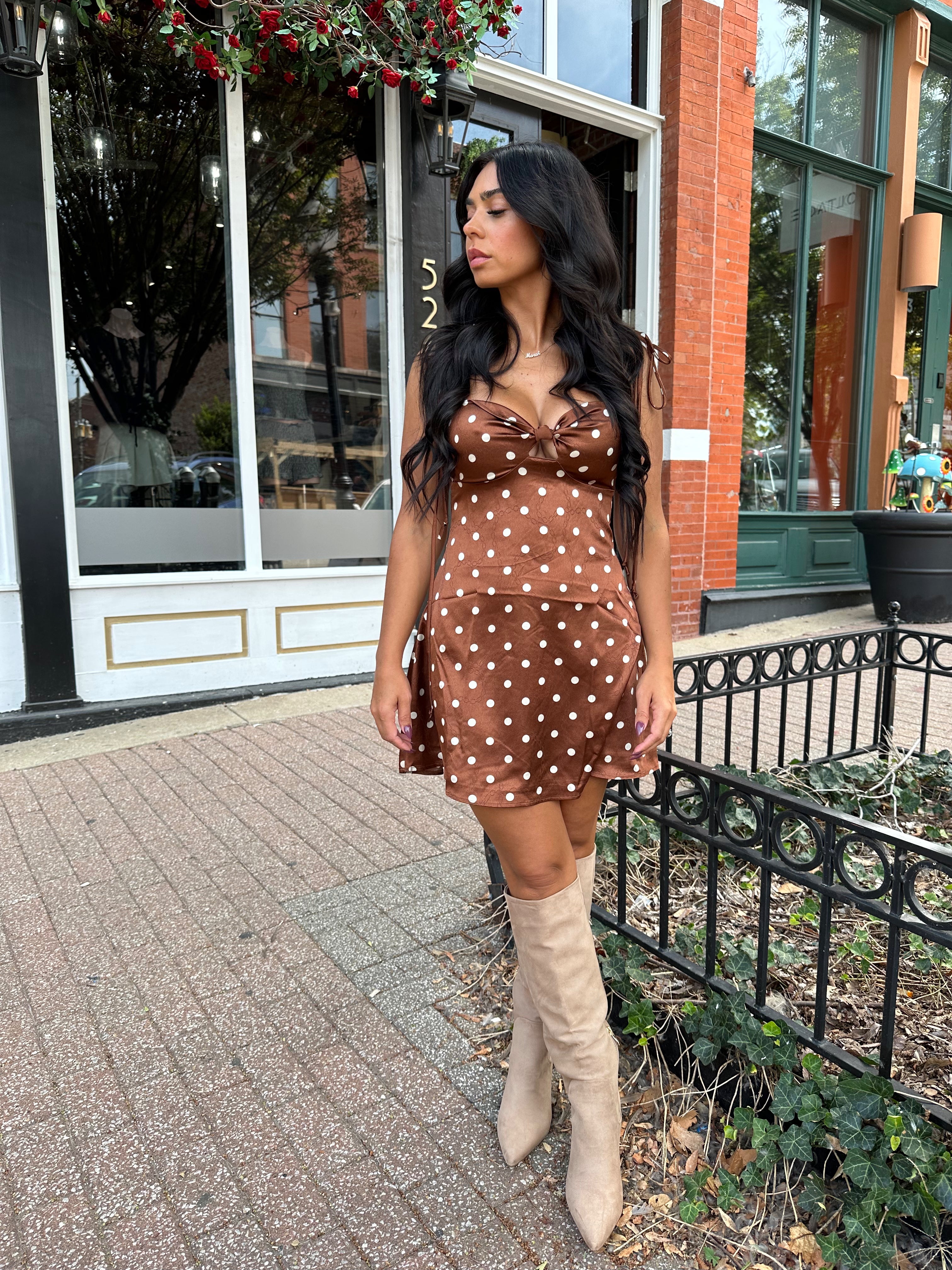 Woman wearing copper brown satin mini dress with white polka dots and self tie straps.