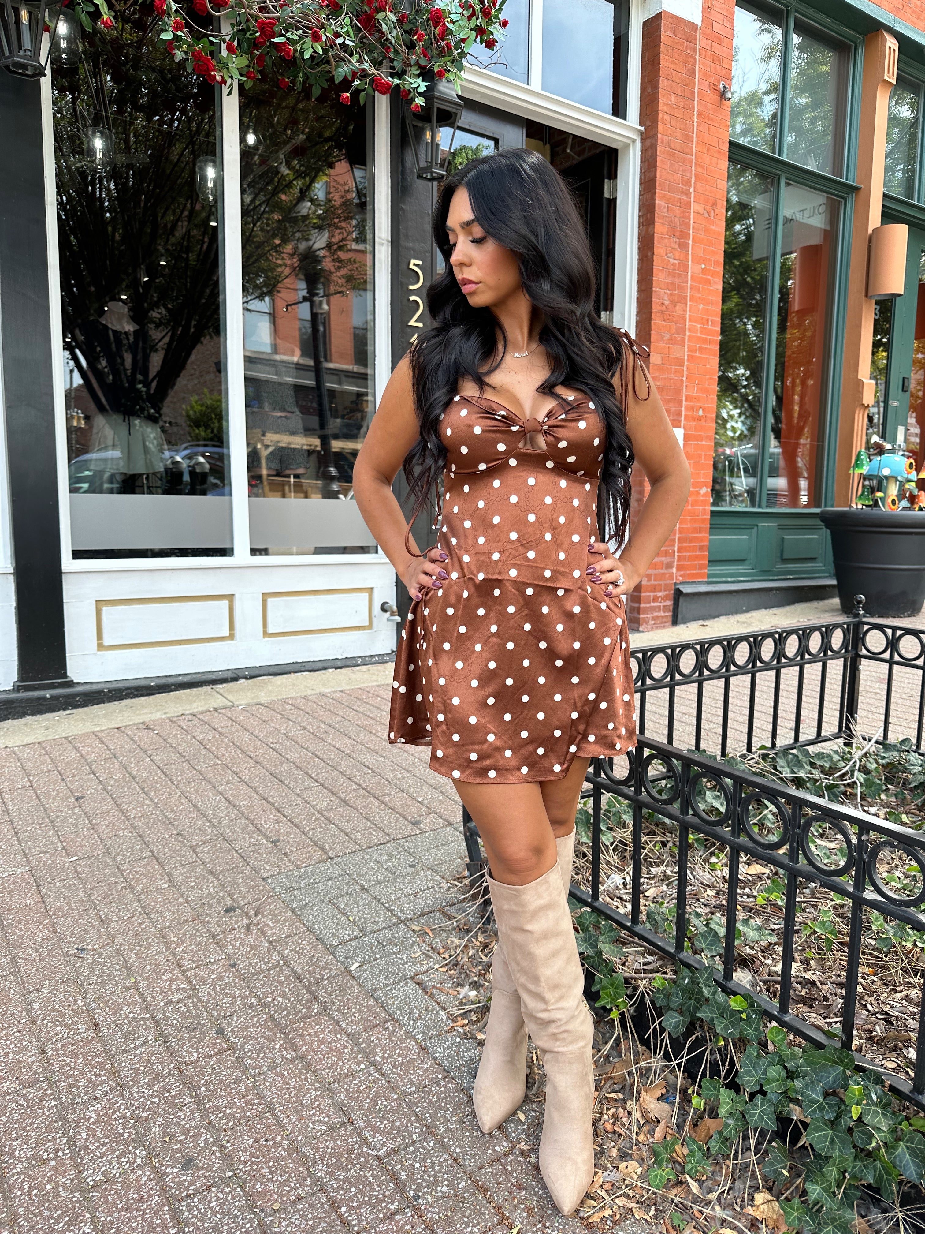 Woman wearing copper brown satin mini dress with white polka dots and self tie straps.