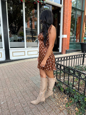 Woman wearing copper brown satin mini dress with white polka dots and self tie straps.