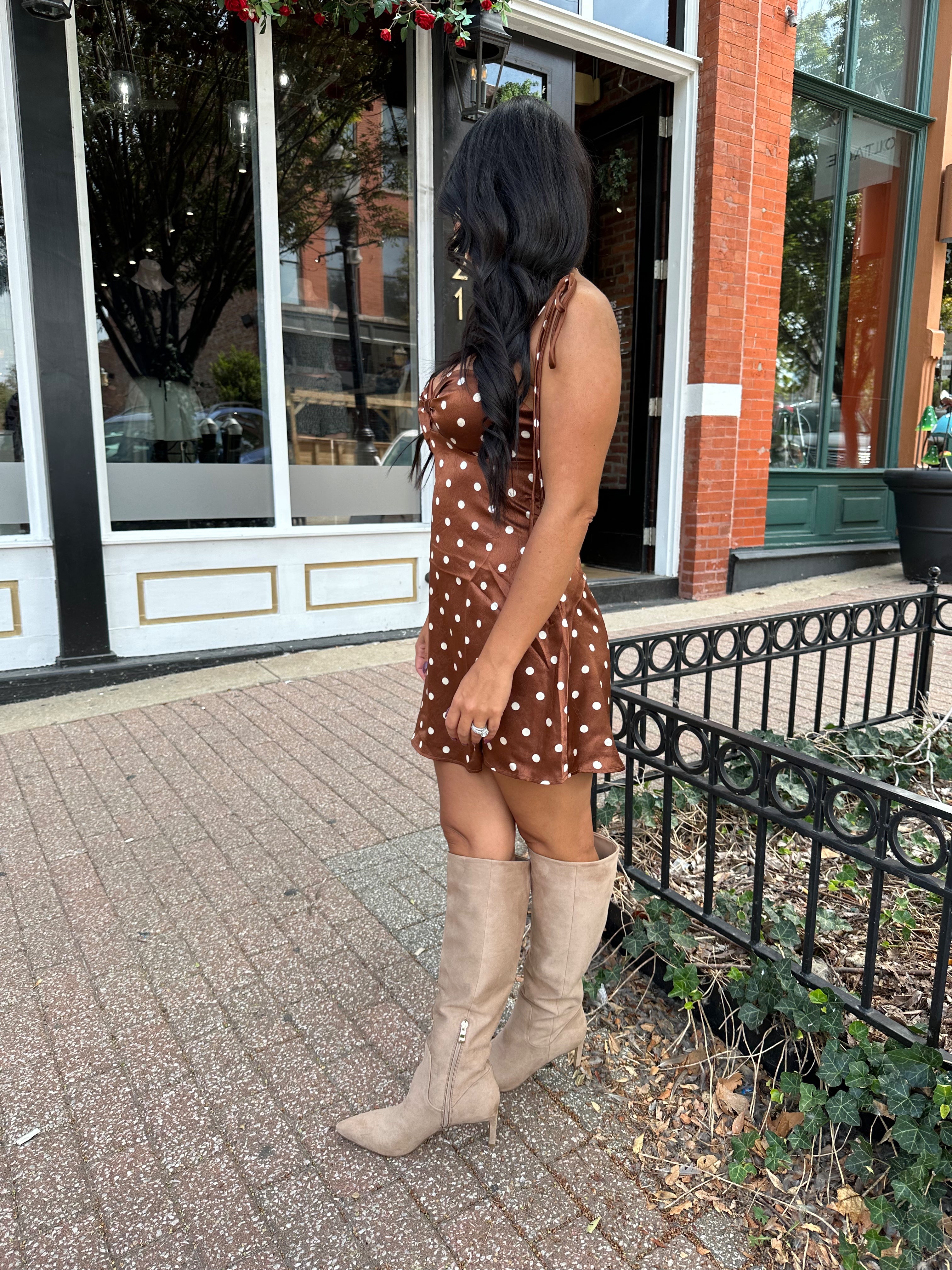 Woman wearing copper brown satin mini dress with white polka dots and self tie straps.