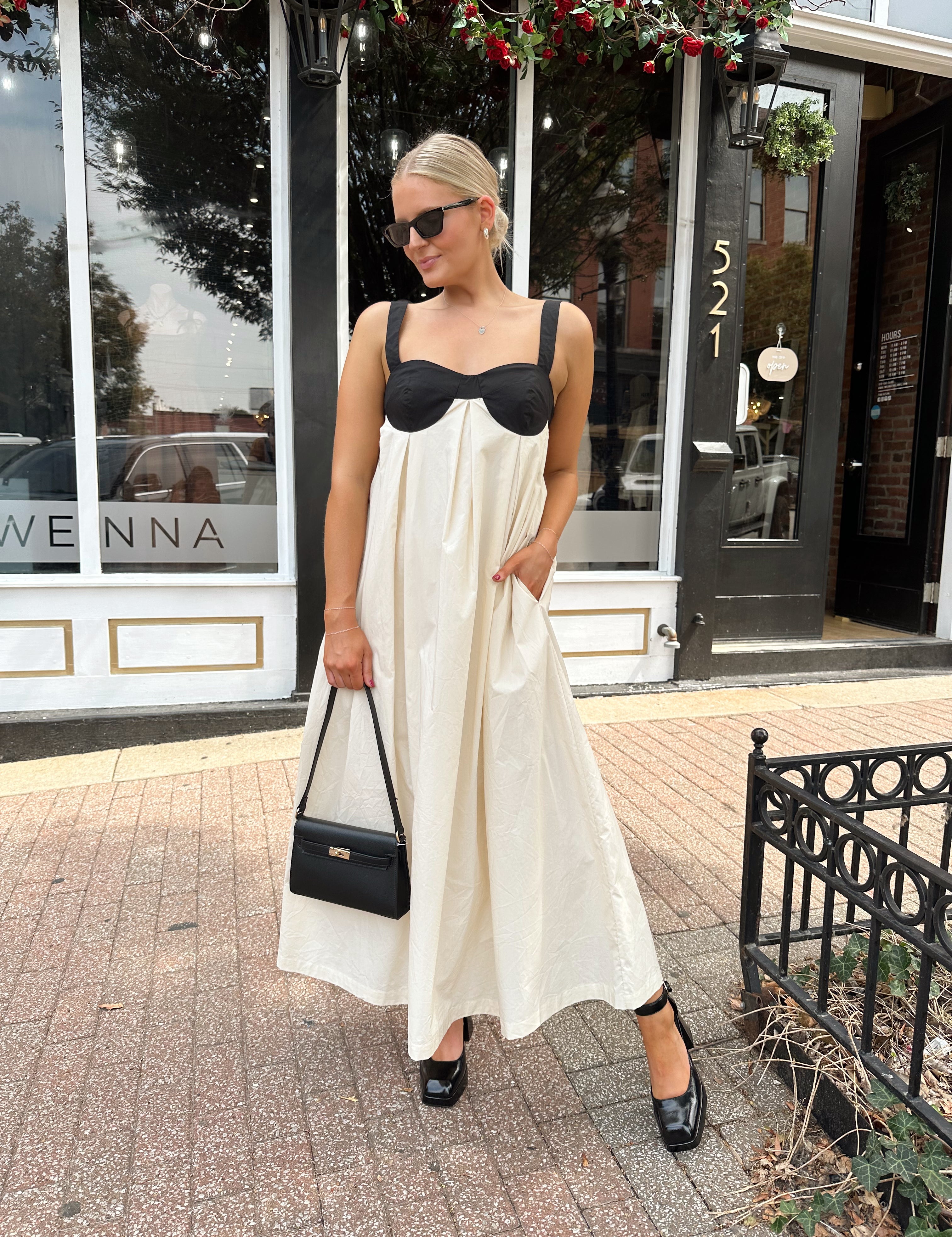 Woman wearing two tone maxi dress with black top and beige bottom with tie back. 