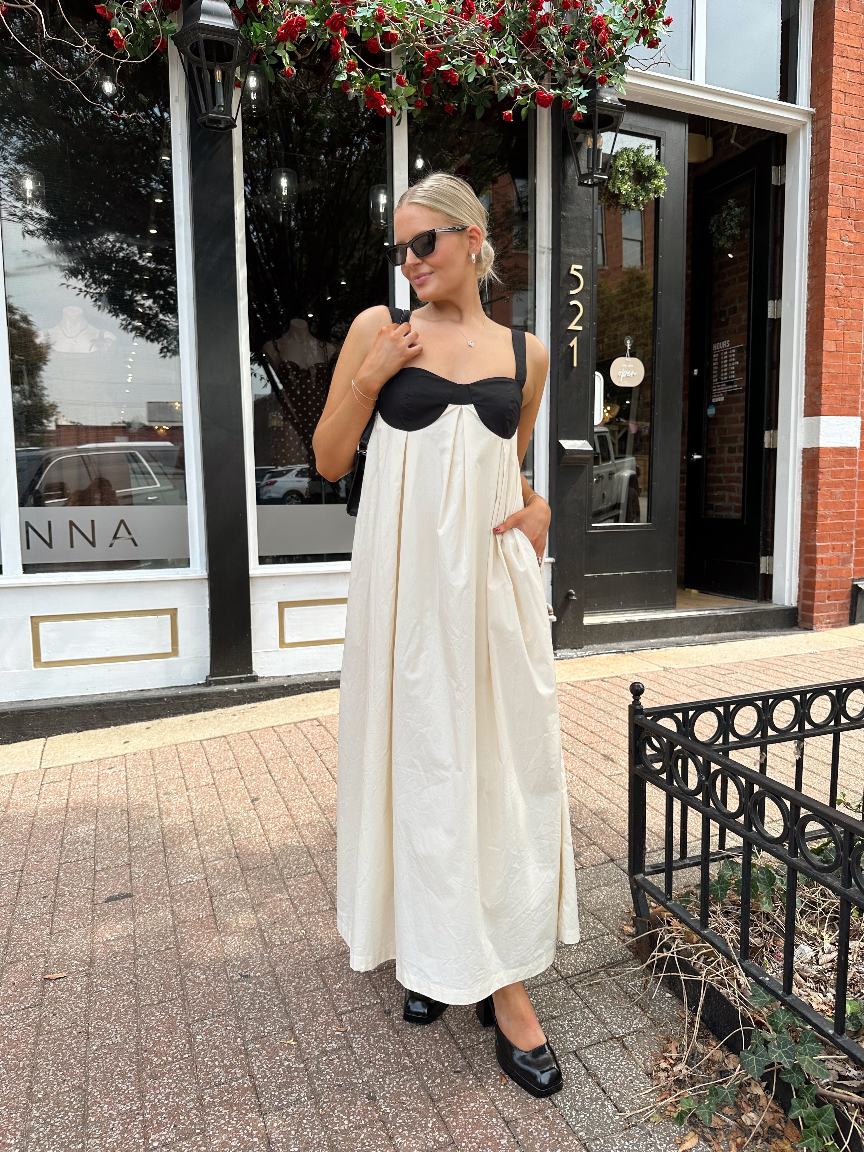 Woman wearing two tone maxi dress with black top and beige bottom with tie back. 
