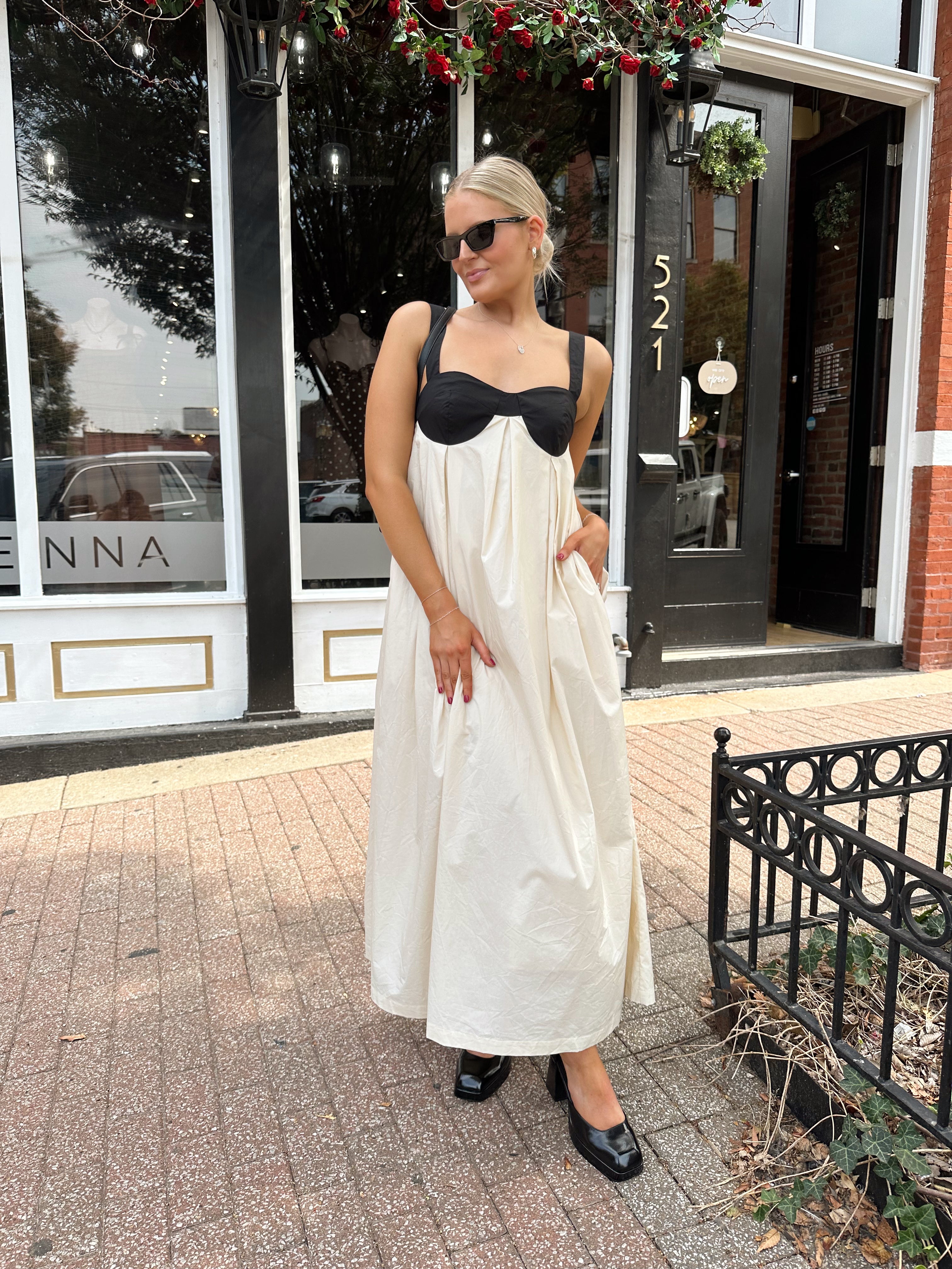 Woman wearing two tone maxi dress with black top and beige bottom with tie back. 