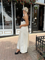 Woman wearing two tone maxi dress with black top and beige bottom with tie back. 