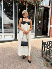 Woman wearing two tone maxi dress with black top and beige bottom with tie back. 