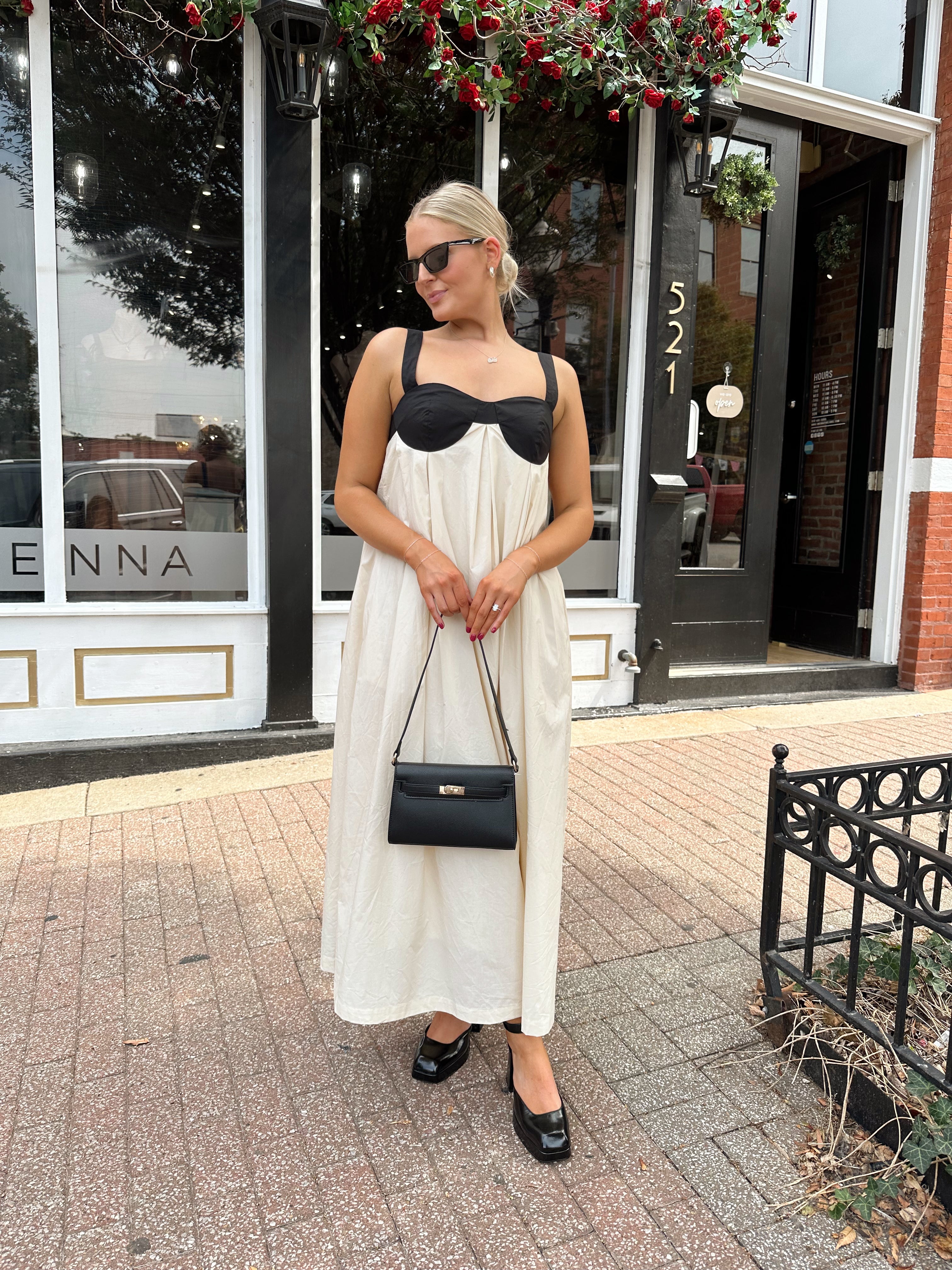 Woman wearing two tone maxi dress with black top and beige bottom with tie back. 