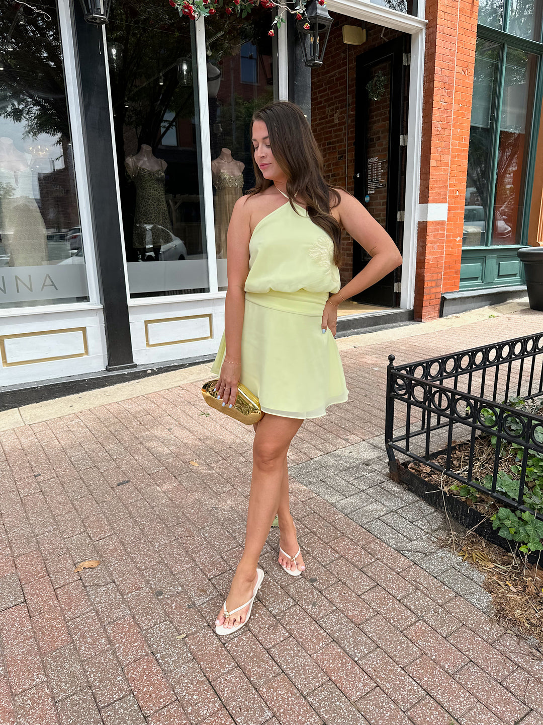 Woman wearing yellow chiffon halter mini dress with beaded detailing, open back with strap detail. 